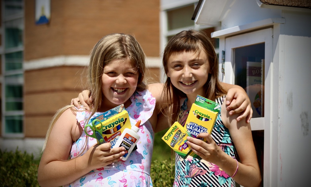 Two Students Hold School Supplies
