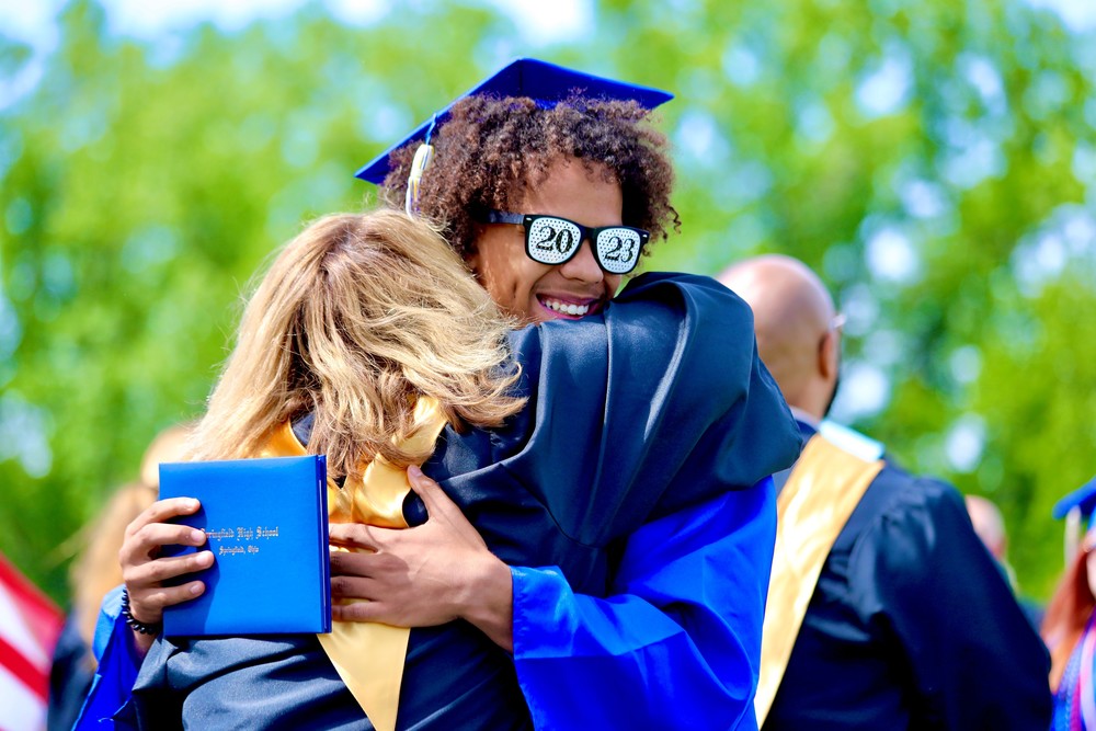 A Springfield High School graduate hugs an administrator as he walks across the stage