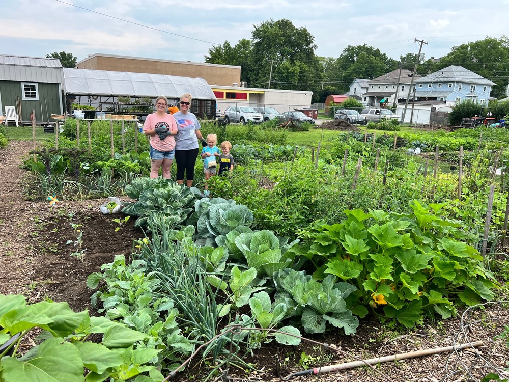A family stands with their parent educator in the community garden space