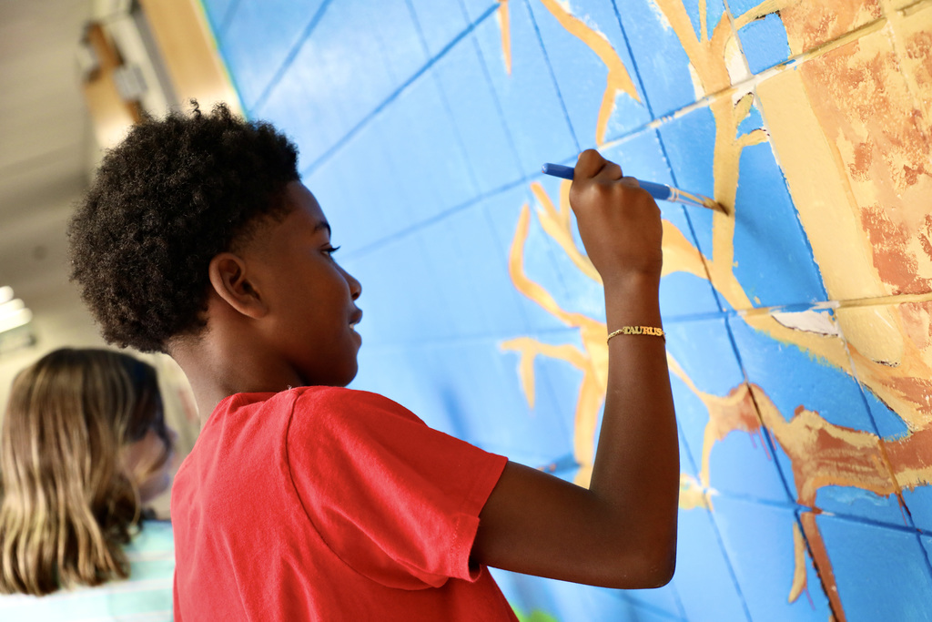 A Perrin Woods student paints a section of the new tree mural in the school's main hallway